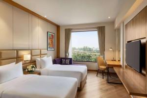 a hotel room with two beds and a flat screen tv at Ramada Encore by Wyndham Amritsar Airport in Amritsar
