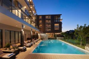 a hotel with a swimming pool and lounge chairs at Hilton Garden Inn Busselton in Busselton