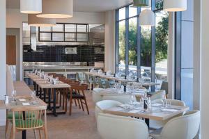 a dining room with tables and chairs and windows at Hilton Garden Inn Busselton in Busselton