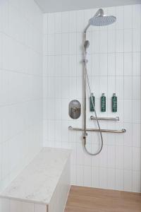 um chuveiro numa casa de banho em azulejos brancos com um balcão em Hilton Garden Inn Busselton em Busselton