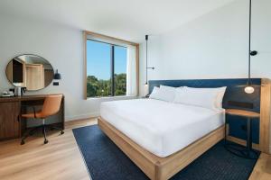a bedroom with a bed and a desk and a window at Hilton Garden Inn Busselton in Busselton
