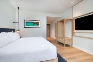 a bedroom with a white bed and a flat screen tv at Hilton Garden Inn Busselton in Busselton