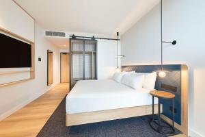 a bedroom with a white bed and a flat screen tv at Hilton Garden Inn Busselton in Busselton