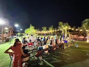 a group of people sitting at tables in a park at night at Bum King Resort Hồ Tràm in Xuyên Mộc