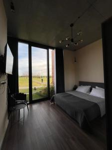 a bedroom with a bed and a large window at Kakheti , Villa Ambassadori Kachreti Golf Resort in Kachretʼi