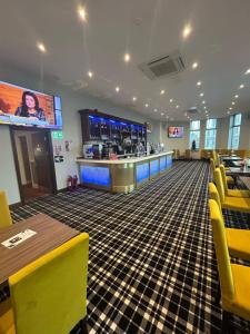 a restaurant with yellow chairs and a bar at The Grand Hotel in Port Talbot