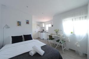 a white bedroom with a large bed and a kitchen at Ático, Studio 300 meters from Cathedral and Giralda in Seville
