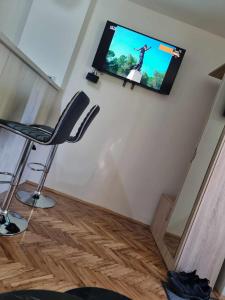 a flat screen tv hanging on a wall with a chair at Apartman Sparta in Sombor
