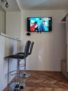 a chair in a room with a television on a wall at Apartman Sparta in Sombor