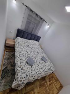 a bedroom with a bed with a blue headboard and a window at Apartman Sparta in Sombor