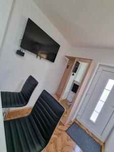 un soggiorno con 2 sedie e una TV a schermo piatto di Apartman Sparta a Sombor Altre 18 foto