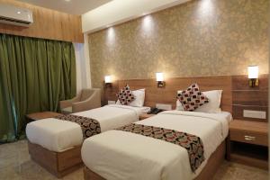 a hotel room with two beds and a chair at HOTEL VKJ INN Aluva in Alwaye