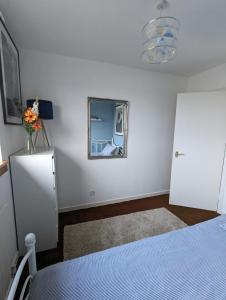 a bedroom with a bed and a mirror and a refrigerator at Single room with Castle view in leafy Edinburgh South in Edinburgh