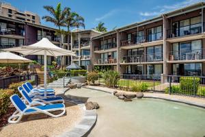 a couple of lounge chairs and a pool in front of a building at Hear the Sea 2 mins from Coolum beach and shops in Coolum Beach