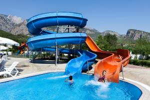 a group of people in a pool with a water slide at Garden Park Beldibi Hotel in Beldibi