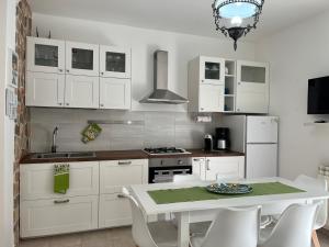 een keuken met witte kasten en een tafel met stoelen bij B&B Euthalia in Riposto
