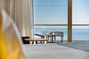a room with a table and chairs and a view of the ocean at Golden Bay Beach Hotel in Larnaca