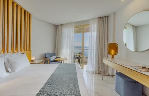 a hotel room with a bed and a view of the ocean at Golden Bay Beach Hotel in Larnaca