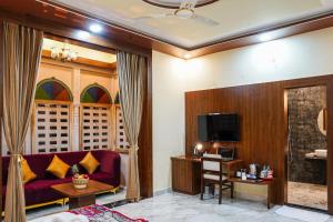 a living room with a red couch and a tv at Hotel Pushkar Legacy in Pushkar