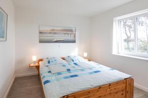a bed in a white room with a window at Achtern Diek in Dagebüll
