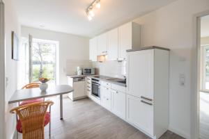 a white kitchen with white cabinets and a table at Achtern Diek in Dagebüll
