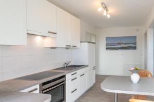 a kitchen with white cabinets and a dining table at Achtern Diek in Dagebüll +2 photos