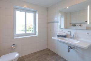 a white bathroom with a sink and a window at Achtern Diek in Dagebüll