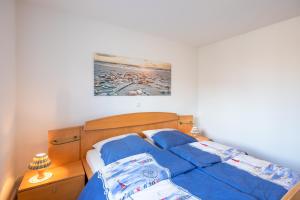 a bed with a blue comforter in a bedroom at Bi uns to Hus in Dagebüll