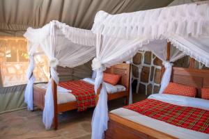 een slaapkamer met 2 bedden en witte gordijnen bij Orng'atuny Mara King Camp in Masai Mara