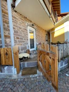 ein Haus mit Holztüren und Ziegelwand in der Unterkunft Appartamento Gioia di Bosco in Carano
