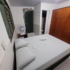 um quarto com uma cama branca e uma ventoinha em Samambaia 01 em Brasília