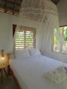 um quarto com uma cama branca e uma janela em Pitico Chalé - Icaraí Kite Village em Icaraí
