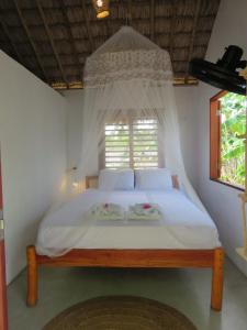 a bedroom with a bed with a mosquito net at Pitico Chalé - Icaraí Kite Village in Icaraí