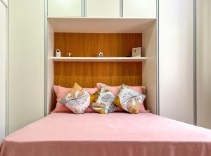 a bedroom with a bed with pink sheets and pillows at Ótimo studio c WiFi a 190m da Praia do Leme - RJ in Rio de Janeiro