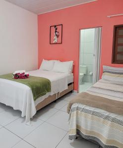 two beds in a room with red walls at POUSADA CAMINHO do MAR in Pôrto de Pedras