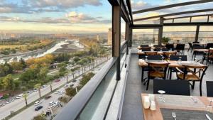 un restaurant avec des tables et des chaises et une vue sur la ville dans l'établissement Türkmen Riverside Hotel Adana, à Adana