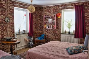 a bedroom with a bed and a chair and windows at Bed and books på Österlens Gästhärbärge in Glemminge