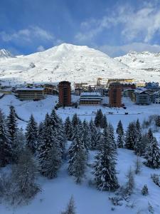 a town in the snow with trees and a mountain at BELLAVISTA APARTMENT in Passo del Tonale