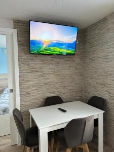 einen weißen Tisch mit Stühlen und einen TV an der Wand in der Unterkunft BELLAVISTA APARTMENT in Passo del Tonale