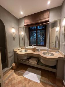 ein großes Bad mit zwei Waschbecken und einem Fenster in der Unterkunft Villa avec piscine et golf in Marrakesch