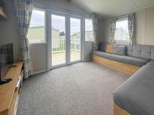a living room with a couch and a large window at Wonderful 8 Berth Caravan With Decking At Valley Farm, Essex Ref 46561v in Great Clacton