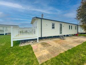a white house with a porch and a yard at Wonderful 8 Berth Caravan With Decking At Valley Farm, Essex Ref 46561v in Great Clacton
