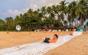 une femme qui se couche sur une serviette sur une plage dans l'établissement Mad Monkey Hostel Nacpan Beach, à El Nido