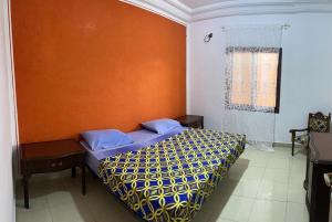 a bedroom with a bed with an orange wall at La Villa Maria in Dakar