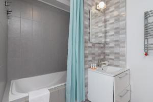 La salle de bains est pourvue d'une baignoire, d'un lavabo et d'une douche. dans l'établissement Starowiślna Apartment with AC & Pet-Friendly by Renters, à Cracovie