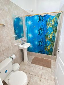 a bathroom with a toilet and a shower curtain at HOSPEDAJE DELFIN AZUL in Puerto Villamil