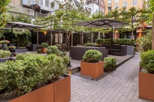 a garden with tables and umbrellas and bushes at The Pavilions Amsterdam, The Toren in Amsterdam