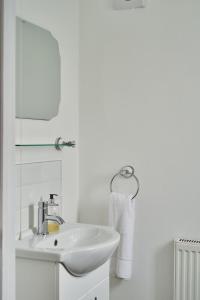 Un baño blanco con lavabo y espejo. en Oakey Cottage - Complimentary Breakfast, en Bourton on the Water