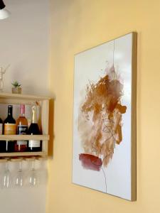 a painting hanging on a wall next to wine bottles at Contêiner 10 Hospedagem in Serra