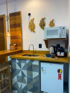 a kitchen with a counter with a sink and a microwave at Pousada Águas da Grota in Penha